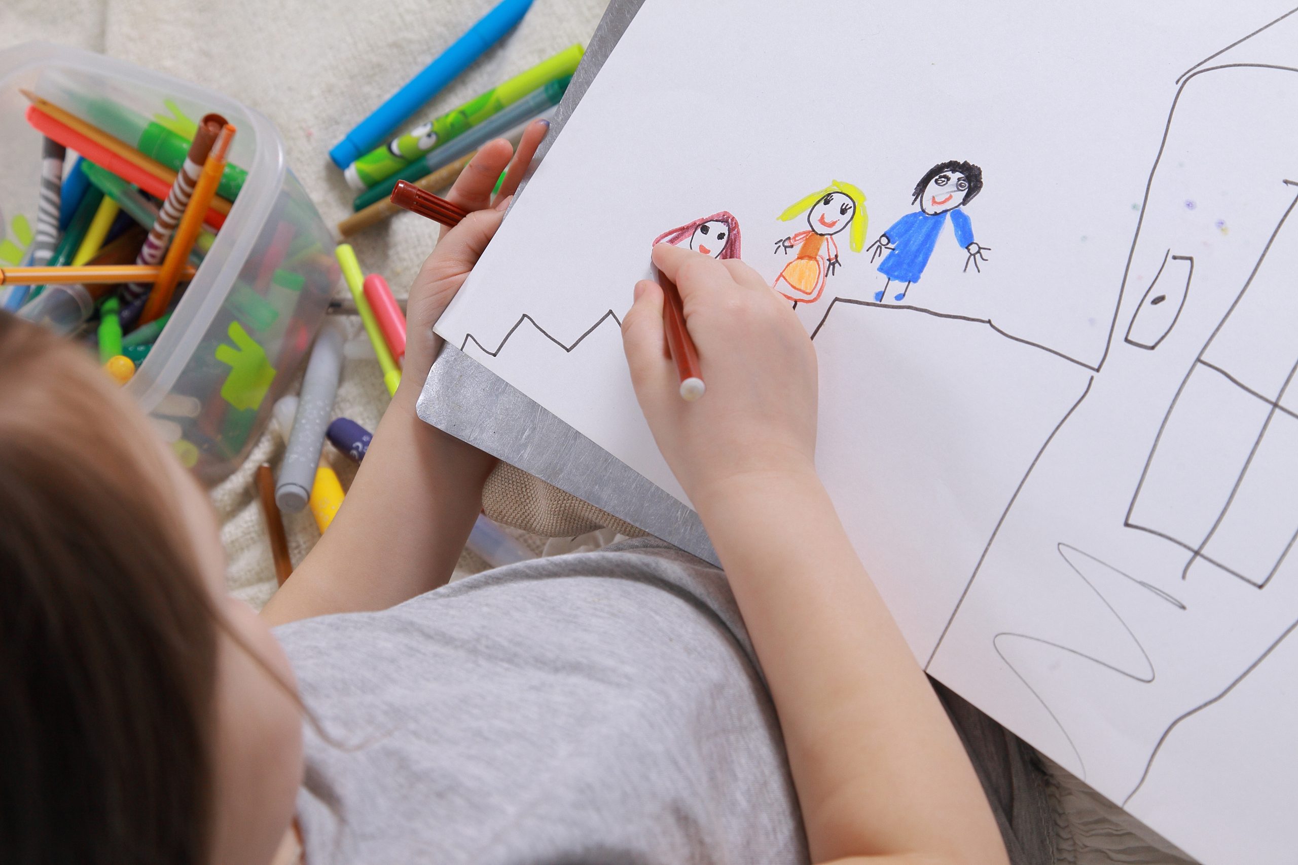 Girl in bright clothing draws a picture of the family. Light roo Counselling and Psychotherapy services in Antrim - NI Counselling