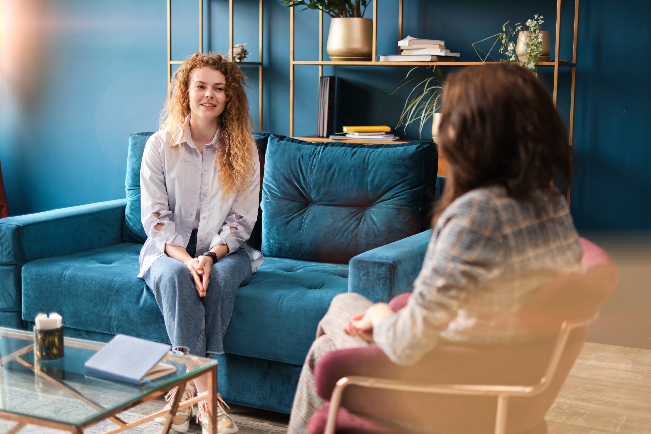 Happy red-haired woman talking to a female psychologist. Discusses her problems, mental trauma. Consultation in the office on the sofa. Positive mood. Counselling and Psychotherapy services in Antrim - NI Counselling